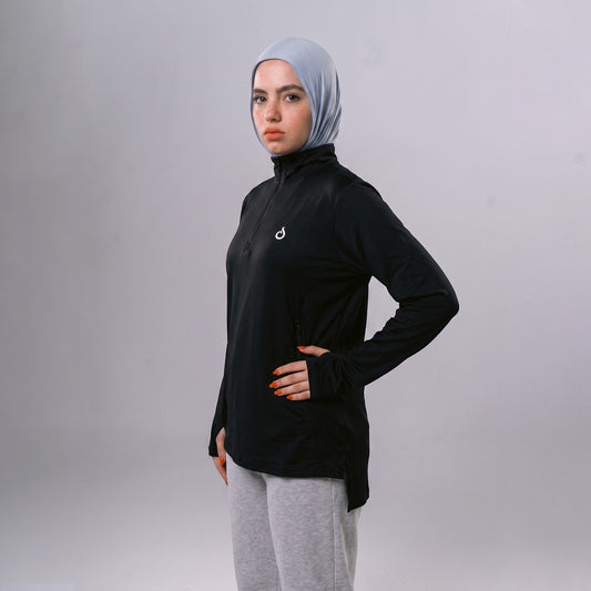 Meryia WASEA Zip Top in black with half-zip neckline, worn by a model in a light blue hijab and grey joggers. | Meryia مِرية