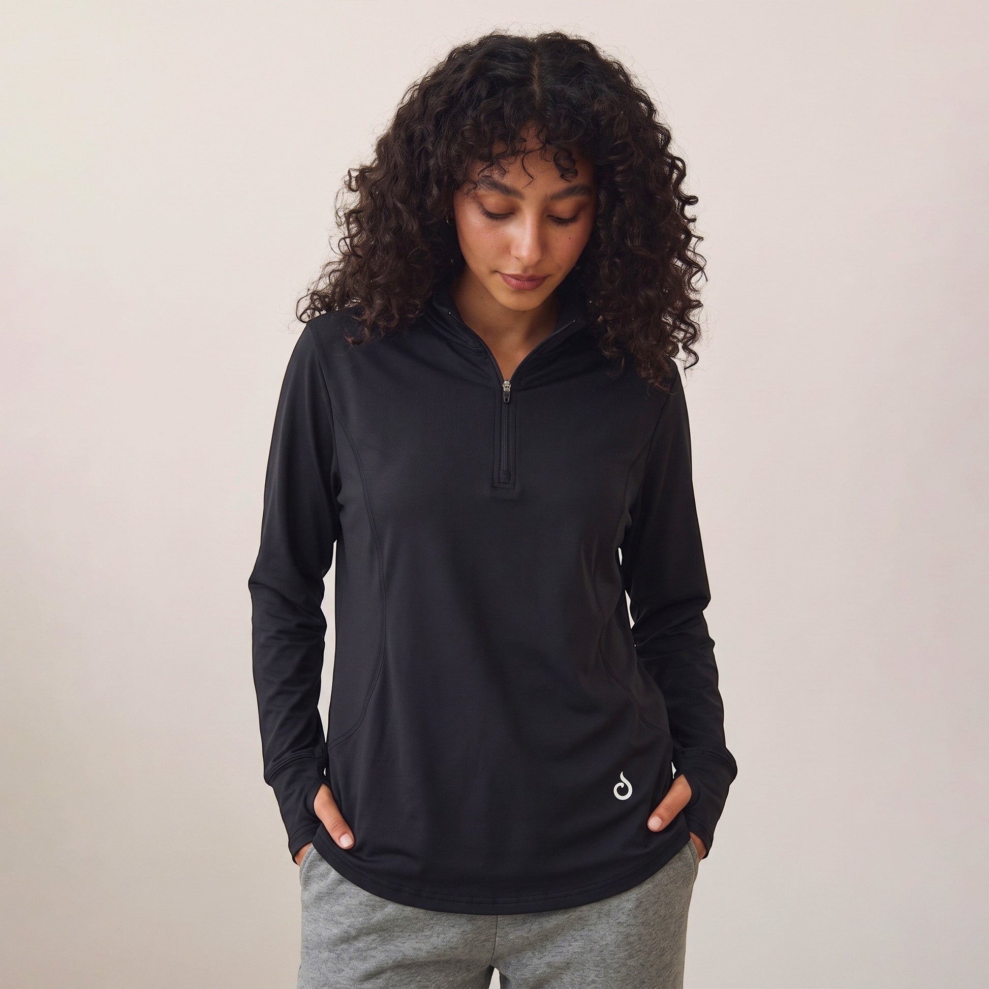Meryia RASM black longline half-zip top with breathable fabric and seam detailing worn by a woman with curly hair