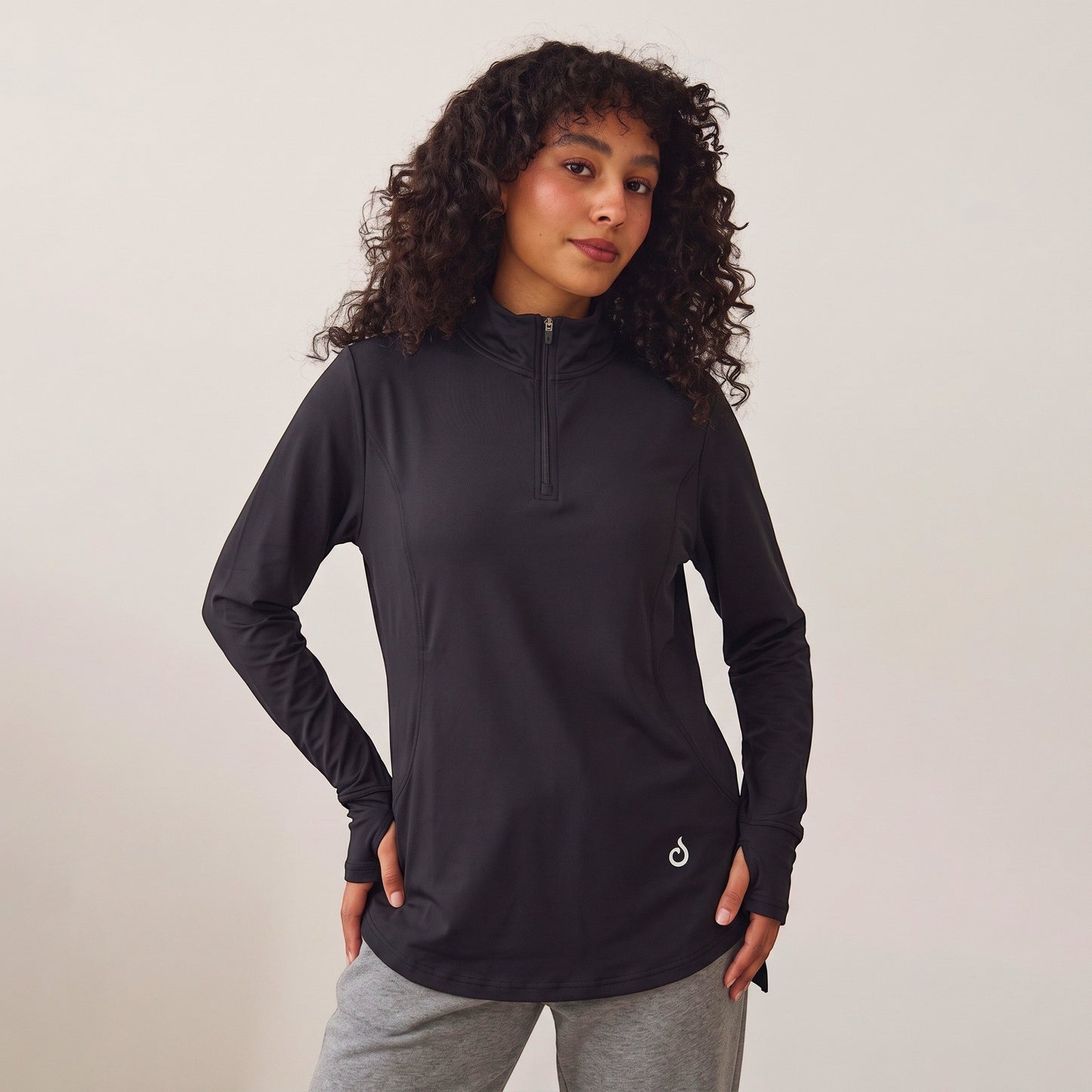 Meryia RASM black longline half-zip top with breathable fabric and seam detailing worn by a woman with curly hair