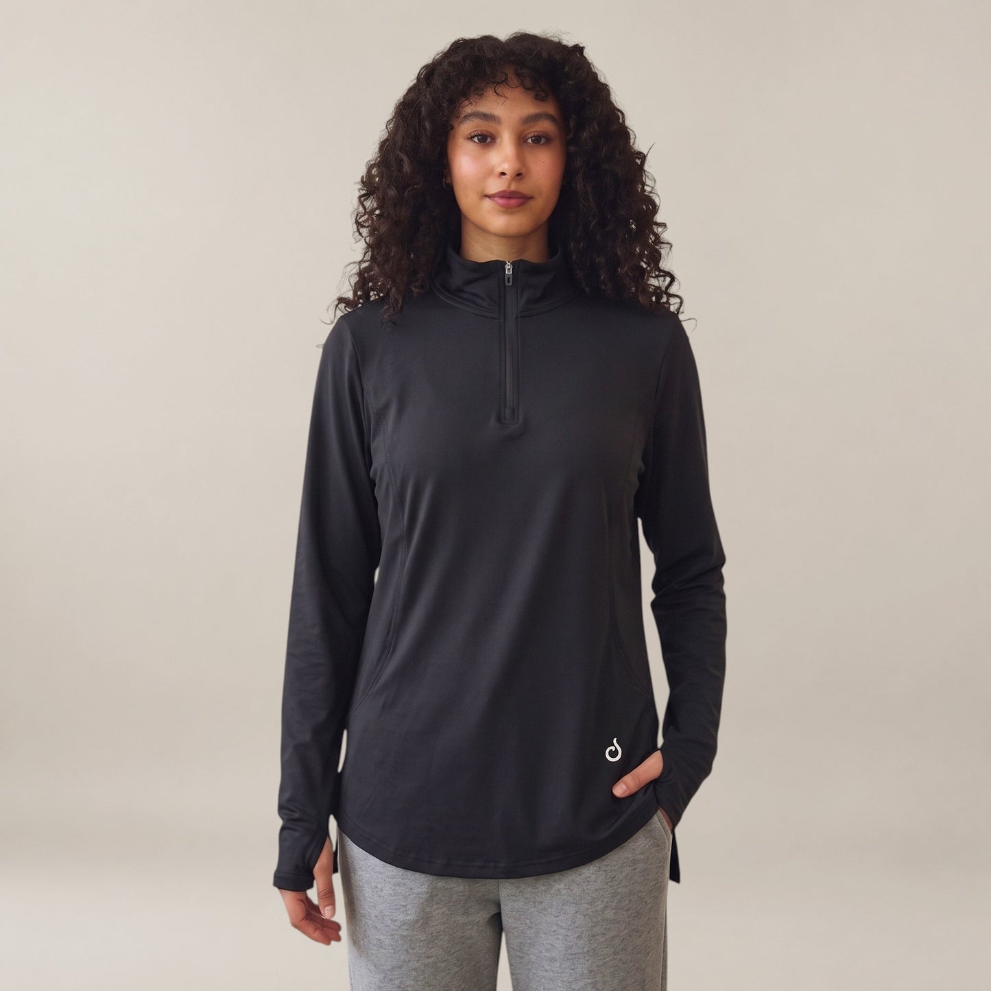 Meryia RASM black longline half-zip top with breathable fabric and thumbholes worn by a woman with curly hair