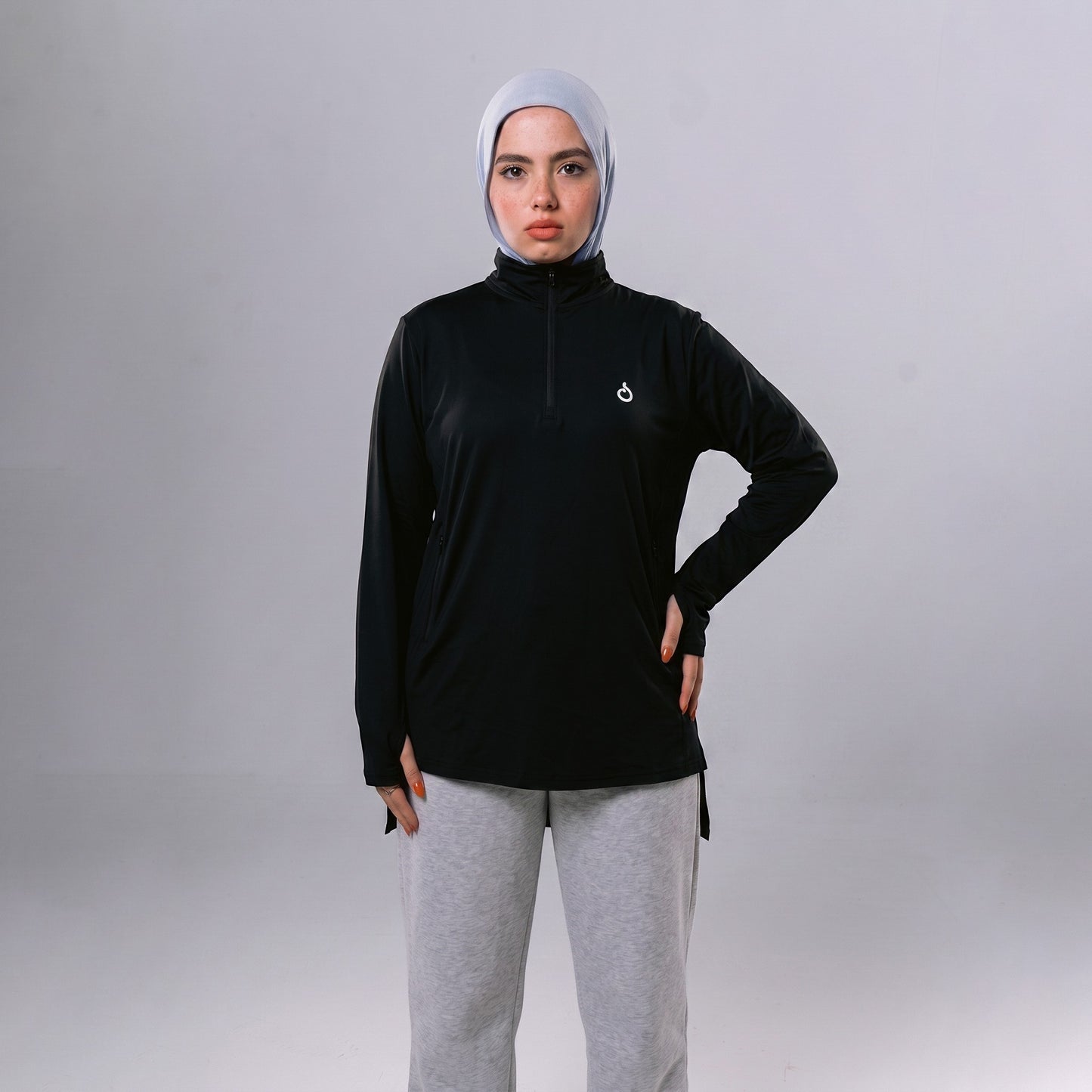 Model wearing a black Meryia WASEA’ Zip Top with a half-zip neckline, long sleeves, and a light blue hijab.