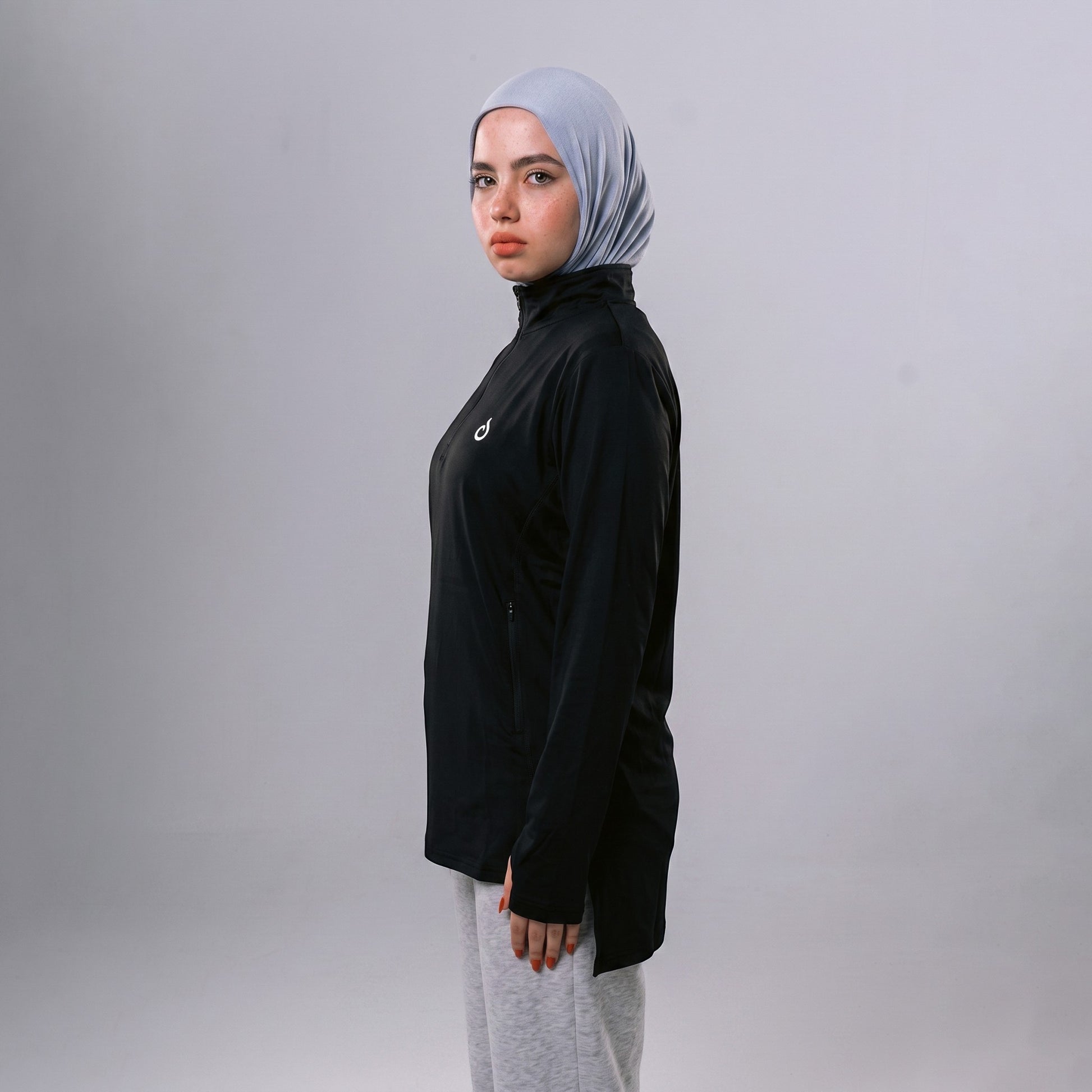 Meryia WASEA Zip Top in black with a half-zip neckline, worn by a model in a light blue hijab and grey joggers.